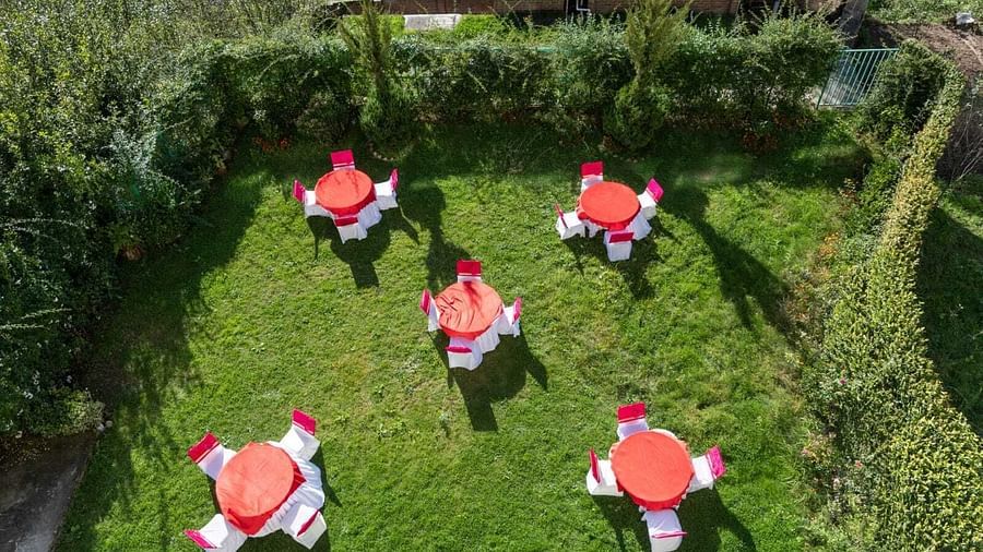 An aerial view of a lush green lawn with five red and white picnic tables arranged in a circular pattern  | DLS Serenity Resort and Spa